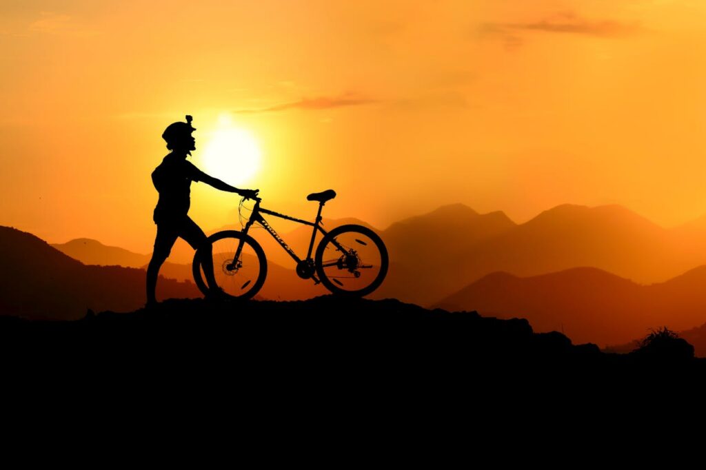 Silhouette of a mountain biker at sunset, showcasing adventure and nature's beauty.