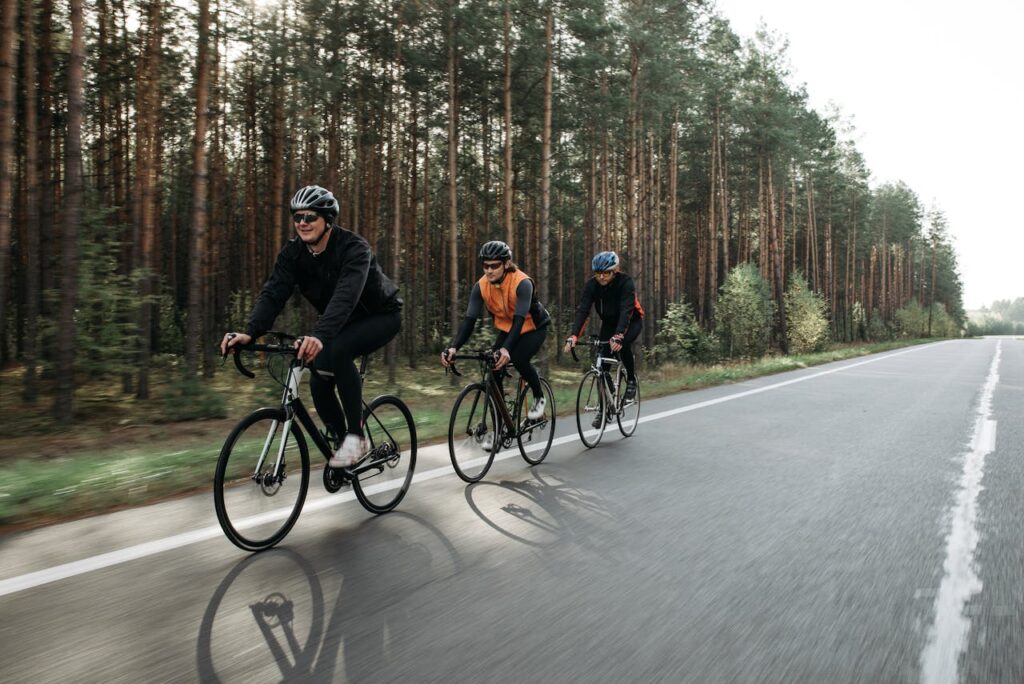Three cyclists enjoying a ride on a road through a scenic forest landscape.